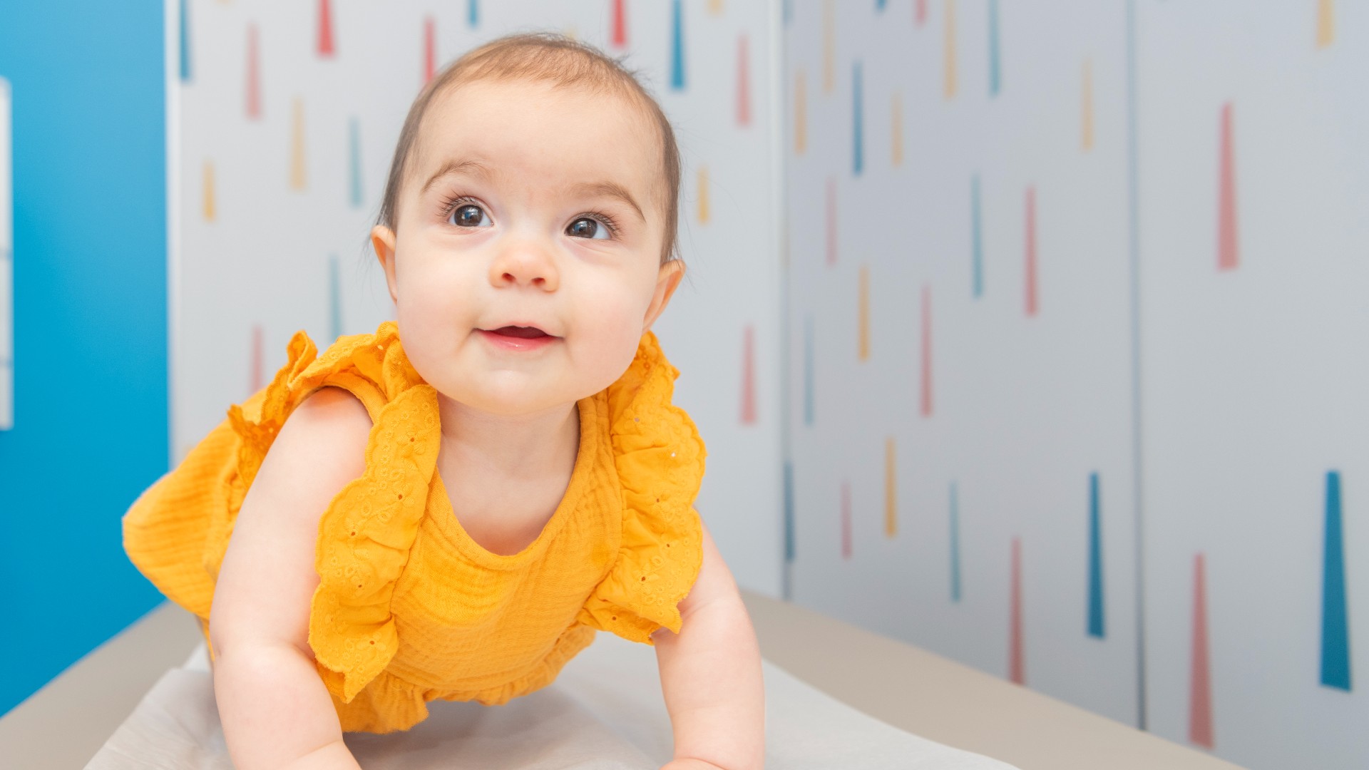 Baby crawling around on exam table smiling